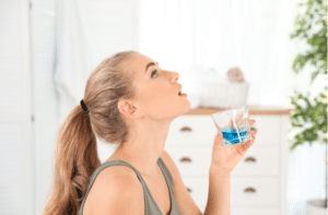 Woman rinsing mouth with mouthwash in bathroom.